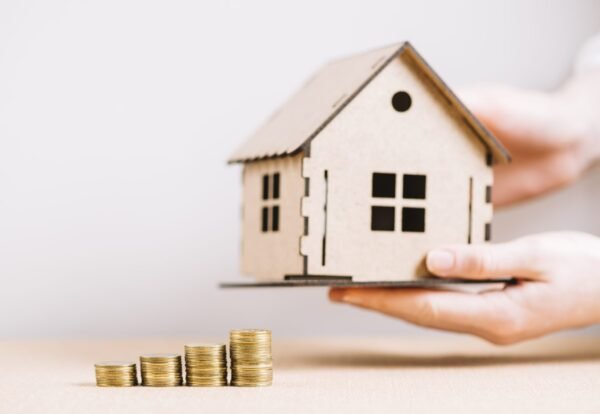 crop-hand-holding-house-near-coins